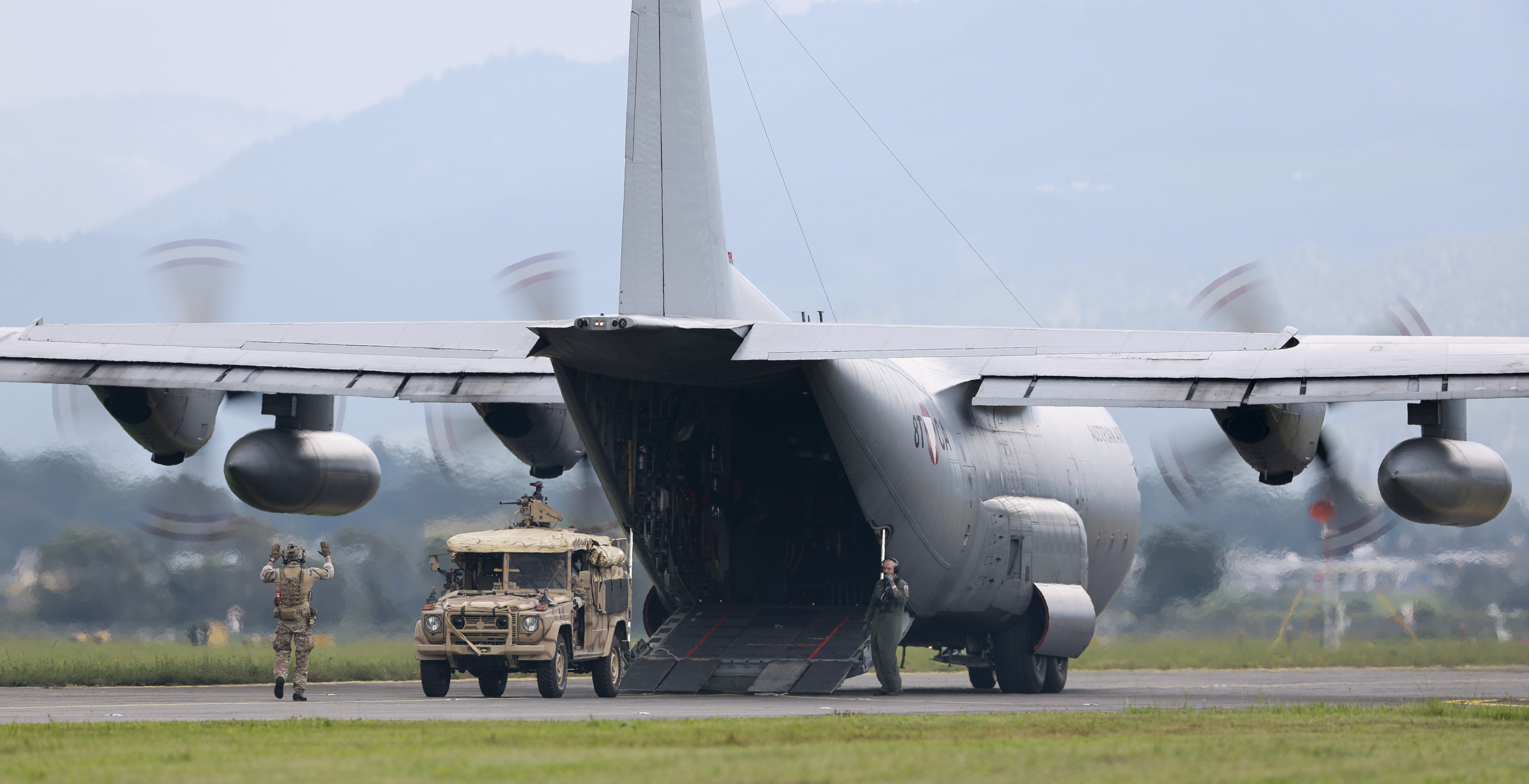 Ein Militärfrachtflugzeug wird auf einer Landebahn unter Mithilfe von Soldaten mit einem Fahrzeug und Versorgungsgütern beladen.